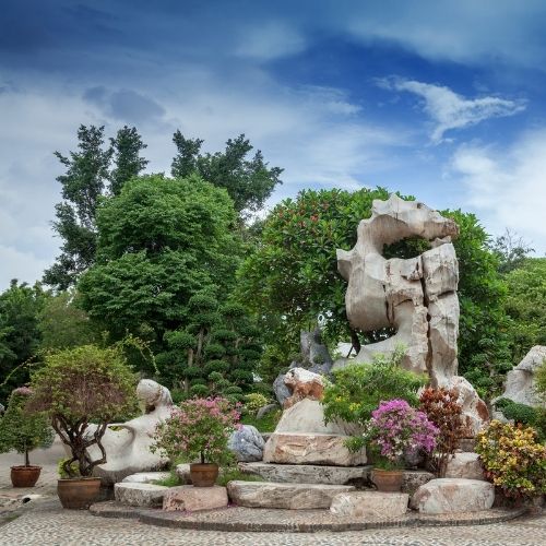 Ein Steingarten mit sehr großen aufgeschichteten Steinen und blühenden Büschen